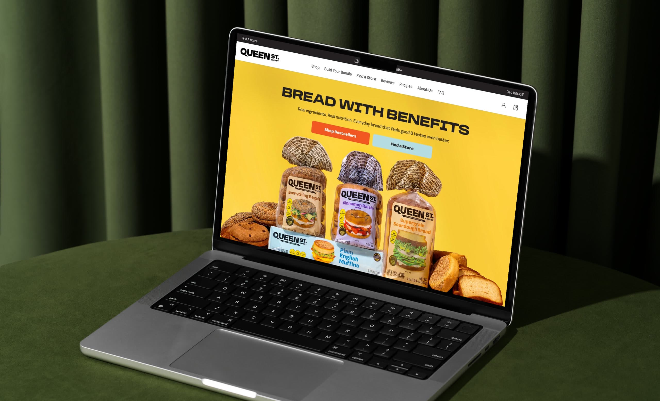 The Queen Street Bakery storefront open on a laptop, photographed against an olive velvet backdrop.